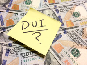 American cash money and yellow post it note with text DUI and question mark in black color aerial view